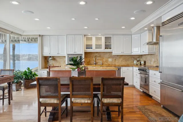 a kitchen with stainless steel appliances granite countertop a dining table chairs refrigerator microwave and cabinets