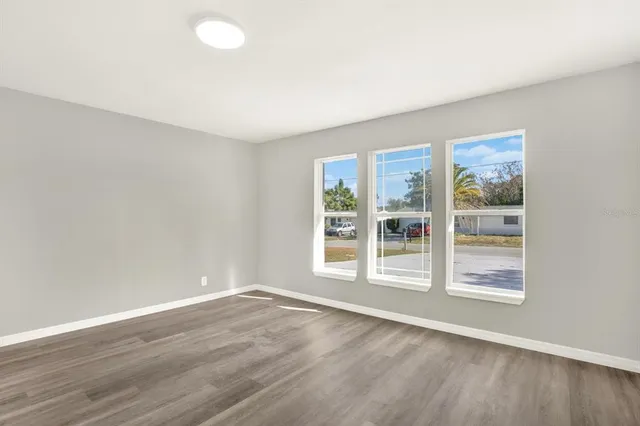 a view of an empty room with wooden floor and a window