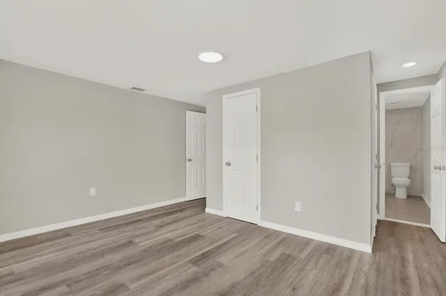 a view of an empty room with wooden floor and a bathroom