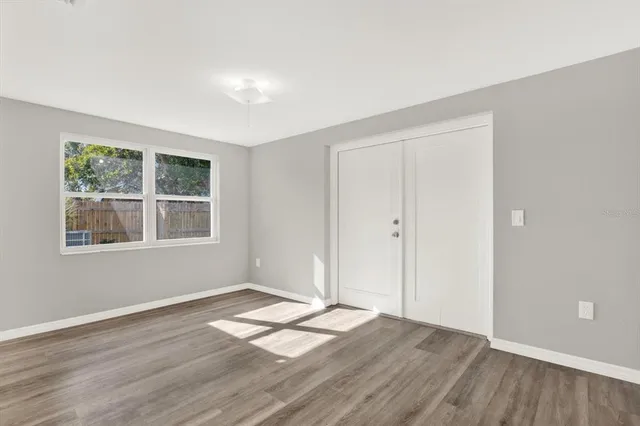 a view of an empty room with wooden floor and a window
