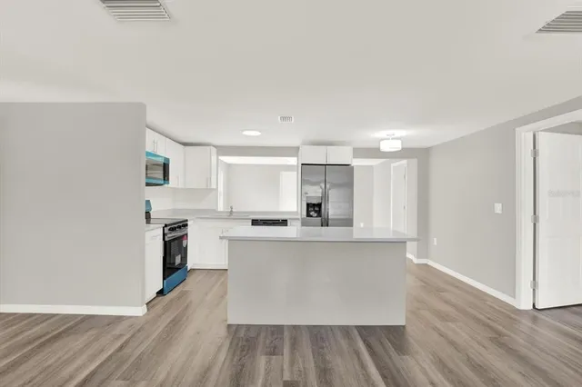 a large kitchen with cabinets wooden floor and stainless steel appliances