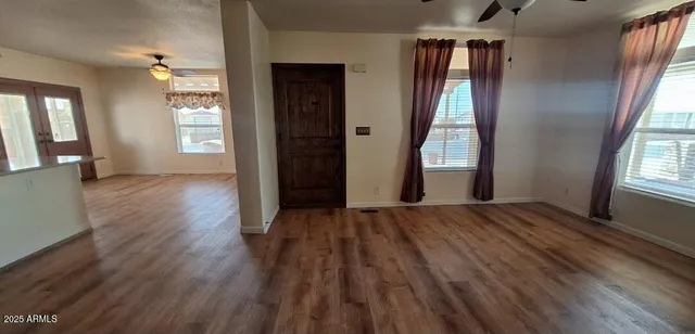 a view of empty room with wooden floor and fan