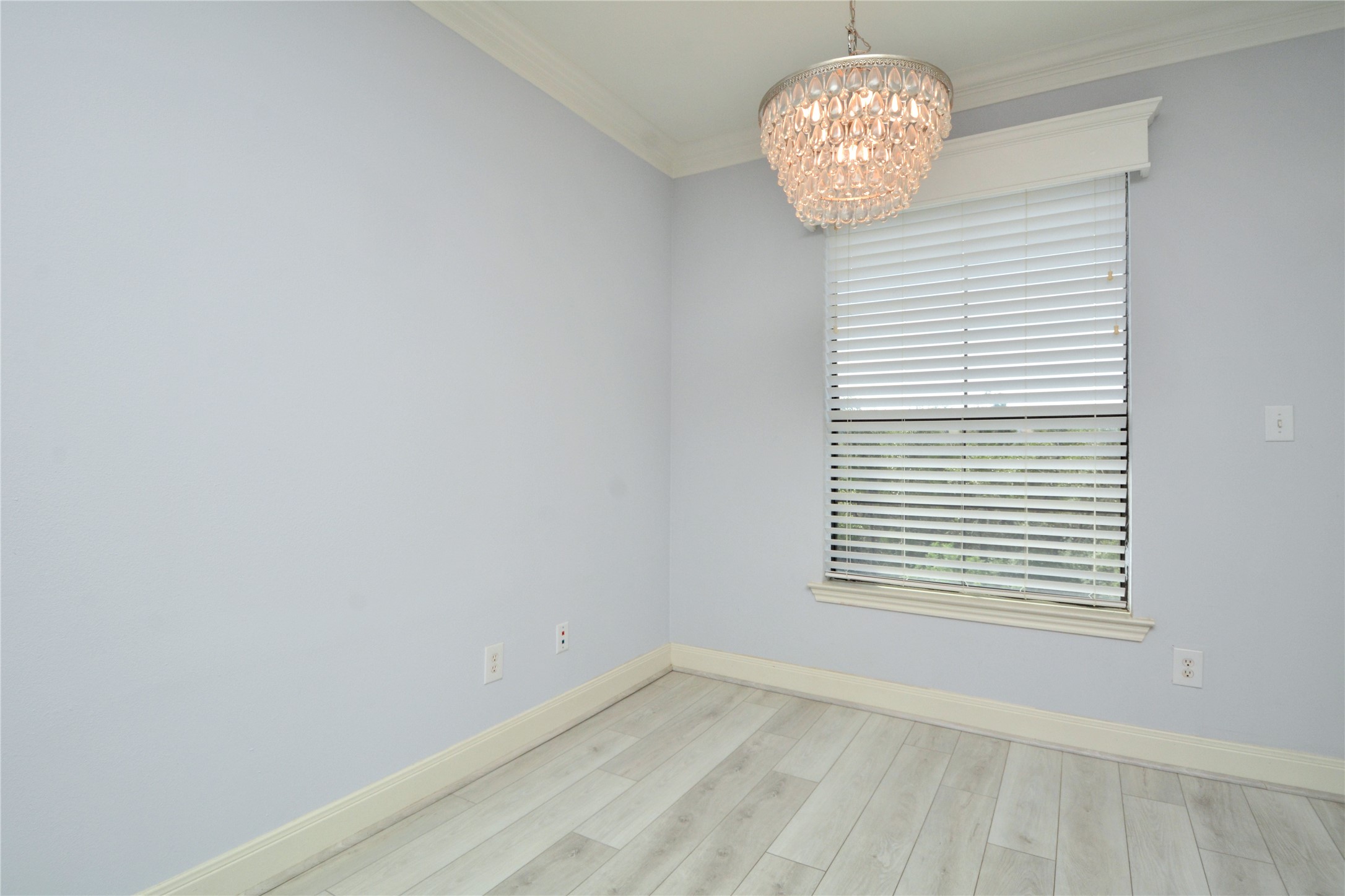 7701 Rialto Boulevard, Unit 124 Austin, TX 78735 - Photo 5 of 22 Room featuring wood-finish flooring, a window with blinds, a decorative light fixture, crown molding, and baseboards