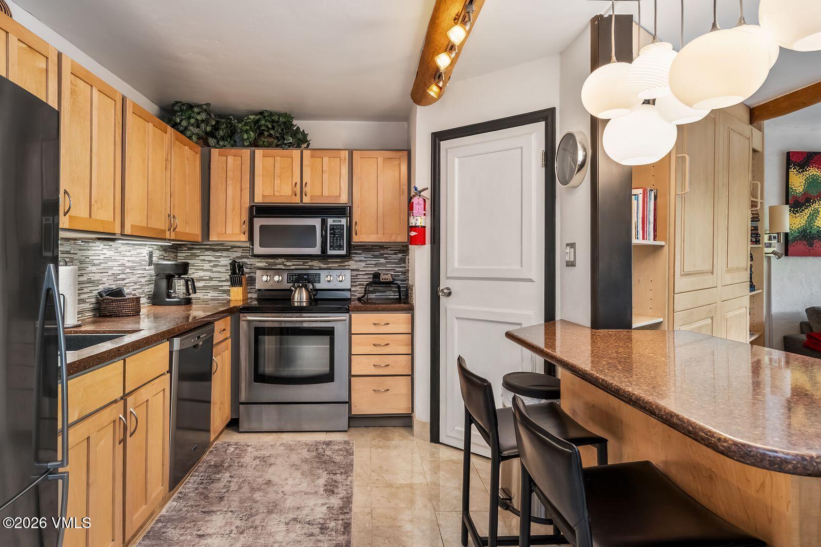 500 South Frontage Road East, Unit 308 Vail, CO 81657 - Photo 9 of 25 a kitchen with stainless steel appliances granite countertop a sink a stove and a refrigerator