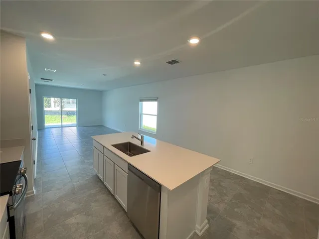 a kitchen with granite countertop a sink and dishwasher a stove with wooden floor
