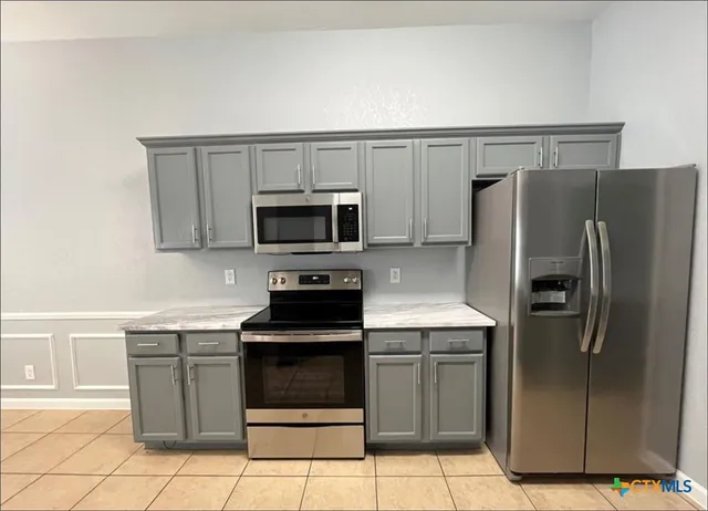 a kitchen with granite countertop a refrigerator and a stove top oven