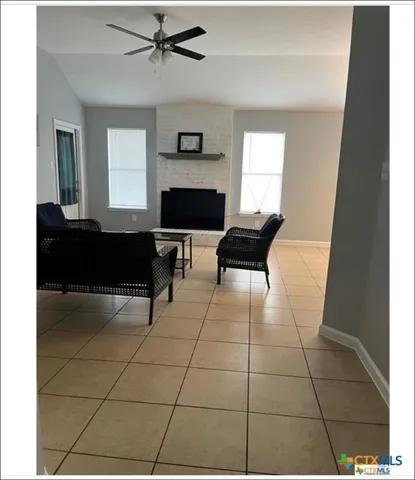 a living room with a black white checkered floor with a gaming machine and a potted plant