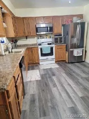 a kitchen with stainless steel appliances granite countertop a refrigerator a stove and a sink