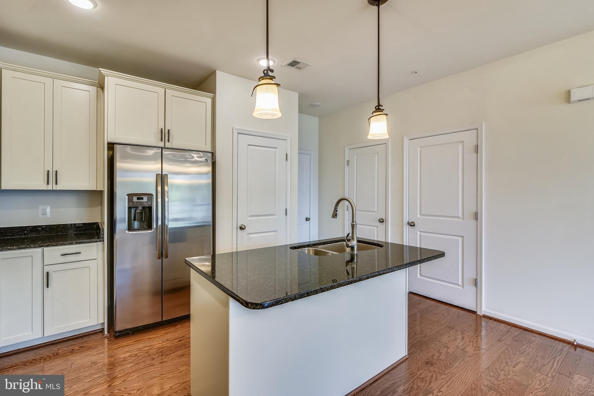 1508 Ribbon Limestone Terrace Southeast Leesburg, VA 20175 - Photo 27 of 79 a kitchen with stainless steel appliances granite countertop a sink a refrigerator a stove and white cabinets with wooden floor