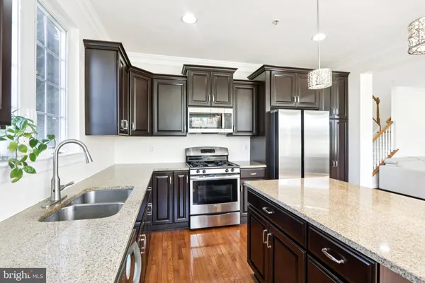 a kitchen with stainless steel appliances granite countertop a sink a stove and a refrigerator