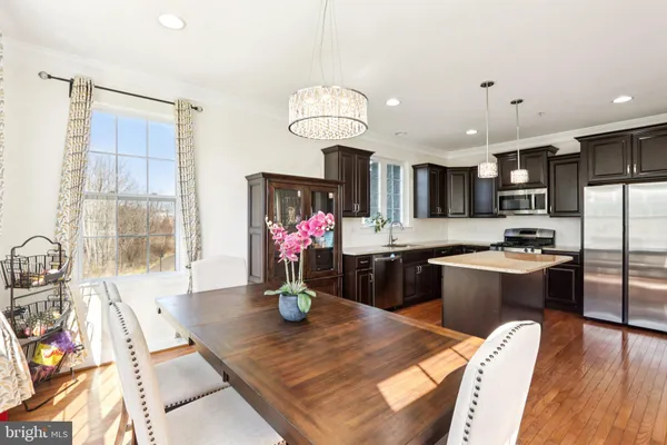 a kitchen with stainless steel appliances wooden floor dining table and chairs