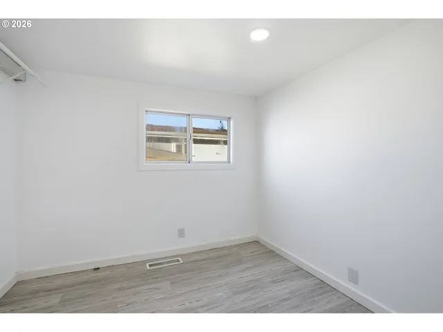 an empty room with wooden floor and window