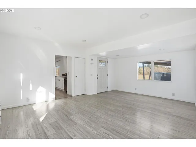 a view of an empty room with window and wooden floor