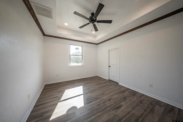 an empty room with wooden floor fan and windows