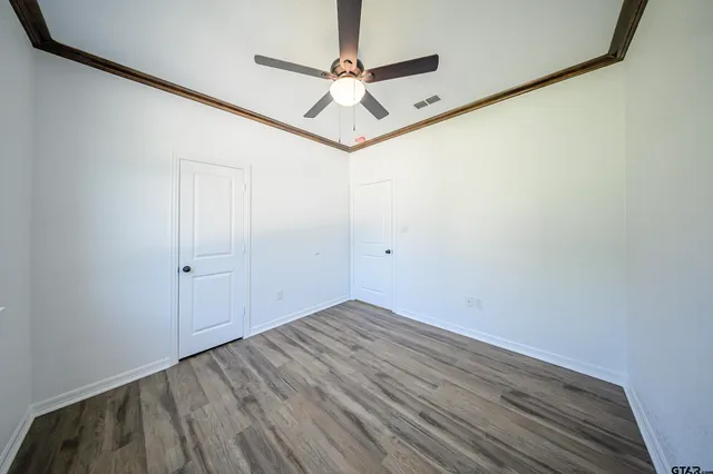 a view of a room with wooden floor and a ceiling fan