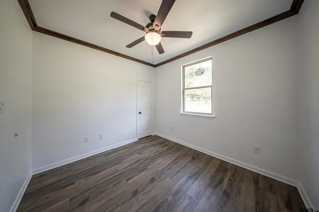 an empty room with windows and ceiling fan