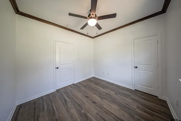 a view of a hallway with wooden floor and a ceiling fan