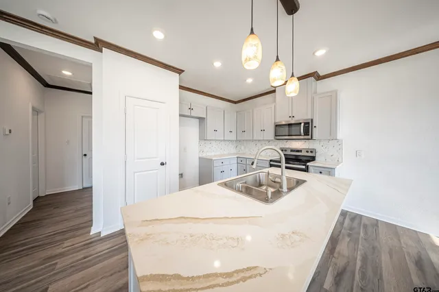 a kitchen with kitchen island a sink stainless steel appliances and cabinets