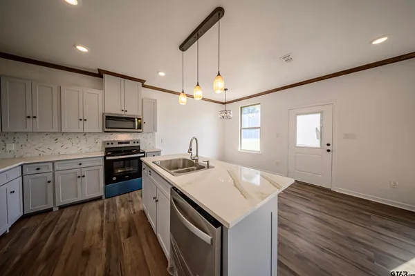 a kitchen with kitchen island a sink a stove and refrigerator