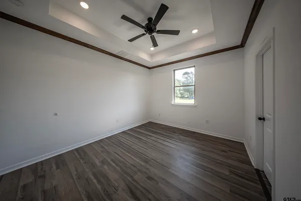 an empty room with wooden floor ceiling fan and windows