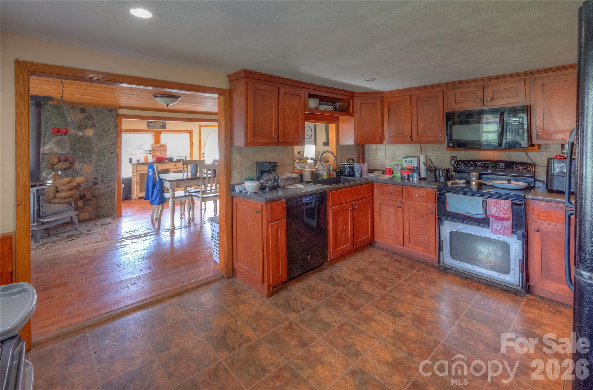 2927 Caney Creek Road Murphy, NC 28906 - Photo 11 of 22 a kitchen with stainless steel appliances granite countertop a stove top oven a sink dishwasher a dining table and chairs with wooden floor