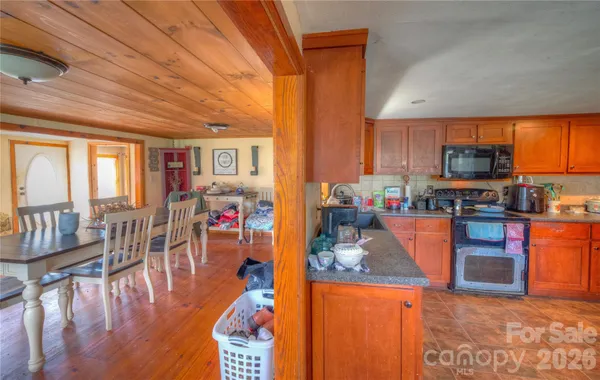 a kitchen with stainless steel appliances granite countertop a stove top oven a sink a dining table and chairs with the view of kitchen