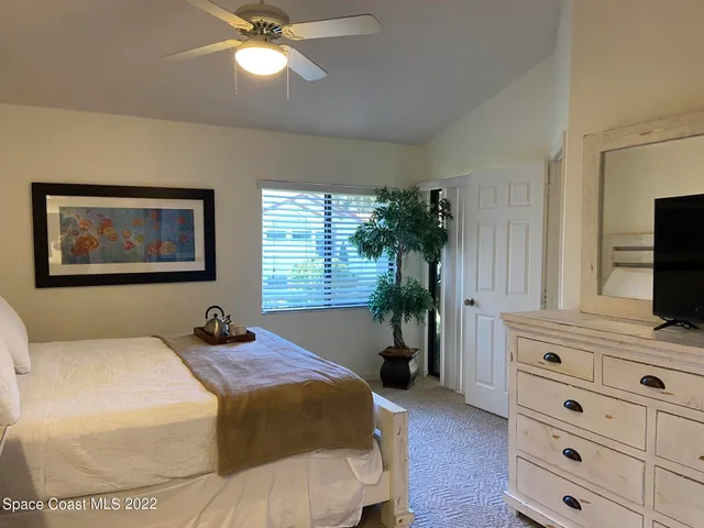 a bedroom with a bed and a flat tv screen on dresser