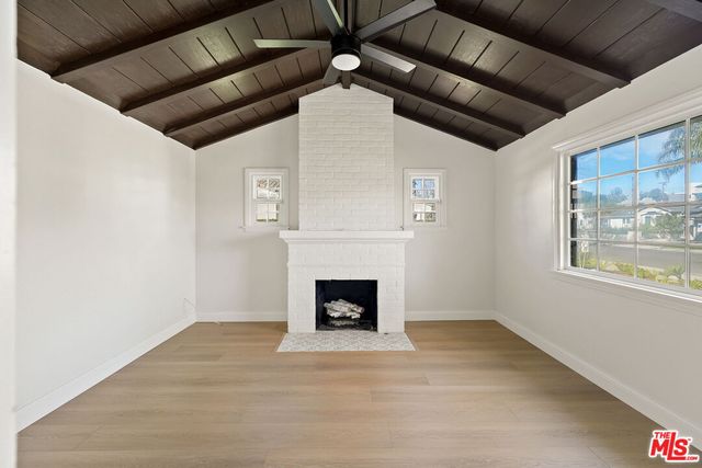 a view of an empty room with wooden floor fireplace and a window