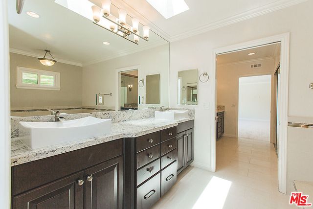 a bathroom with a granite countertop double vanity sink and a mirror
