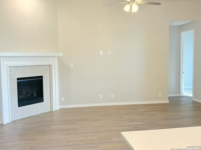 a view of an empty room with wooden floor and fireplace