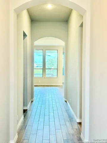 a view of a hallway with wooden floor and a bathroom