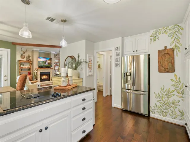 a kitchen with stainless steel appliances granite countertop a refrigerator and a stove top oven with wooden floor