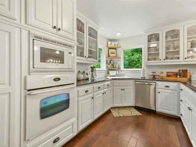 a kitchen with granite countertop white cabinets and white appliances