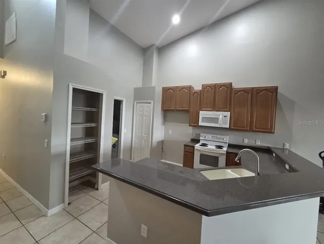 an empty room with chandelier fan and windows