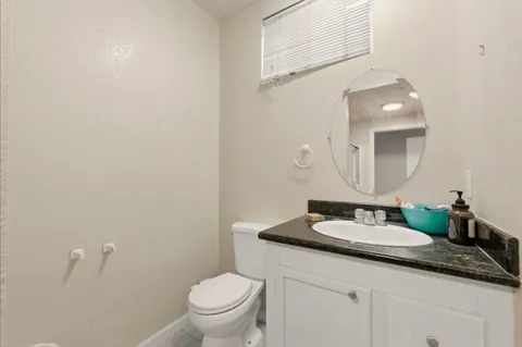 a bathroom with a granite countertop sink and a mirror with toilet