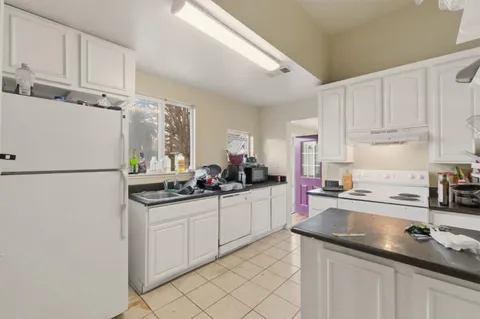 a kitchen with granite countertop a sink refrigerator and cabinets