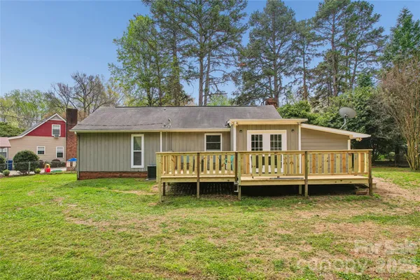 a view of a house with a backyard and a wooden deck