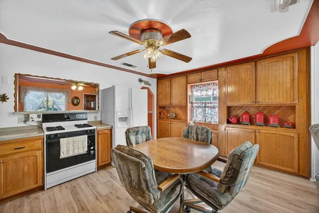 a kitchen with stainless steel appliances granite countertop a stove a refrigerator a dining table and chairs with wooden floor