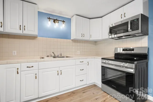 a kitchen with granite countertop white cabinets stainless steel appliances and wooden floor
