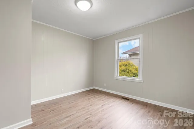 an empty room with wooden floor and window
