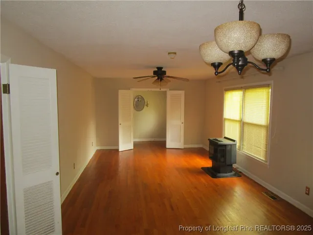 a view of an empty room with a window and wooden floor