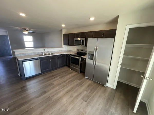 a large kitchen with stainless steel appliances granite countertop a refrigerator and a stove top oven