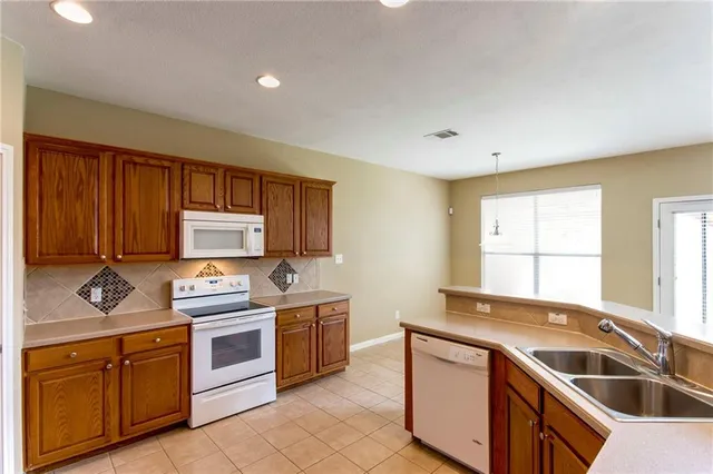 a large kitchen with stainless steel appliances granite countertop a sink and dishwasher a stove a oven with wooden cabinets