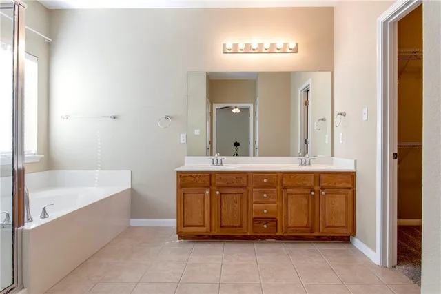a bathroom with a tub sink shower and two mirror