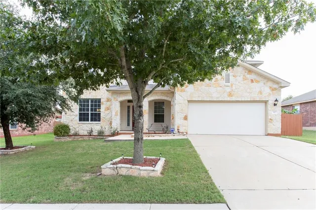 a front view of a house with a yard and trees