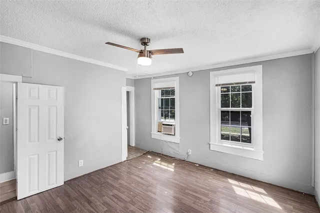 a view of empty room with wooden floor and fan