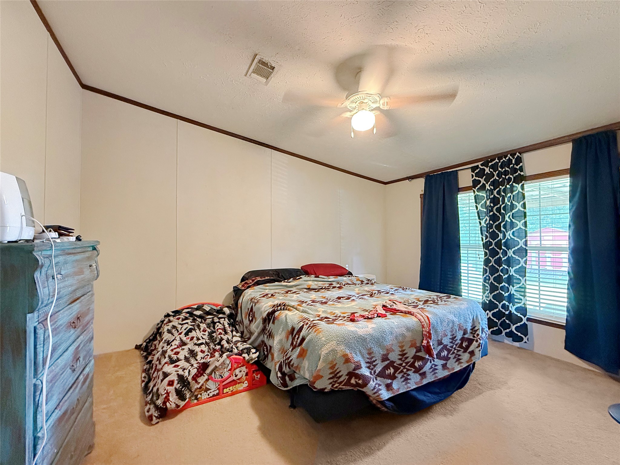845 Caldwell Street Lexington, TX 78947 - Photo 12 of 39 Carpeted bedroom with crown molding, ceiling fan, and a textured ceiling