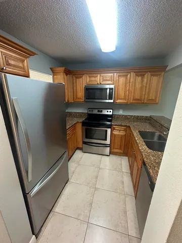 a kitchen with granite countertop a refrigerator and a sink