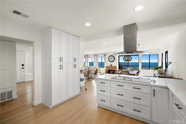 a room with stainless steel appliances kitchen island granite countertop a sink cabinets and wooden floor