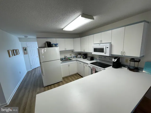 a kitchen with sink a refrigerator and white cabinets